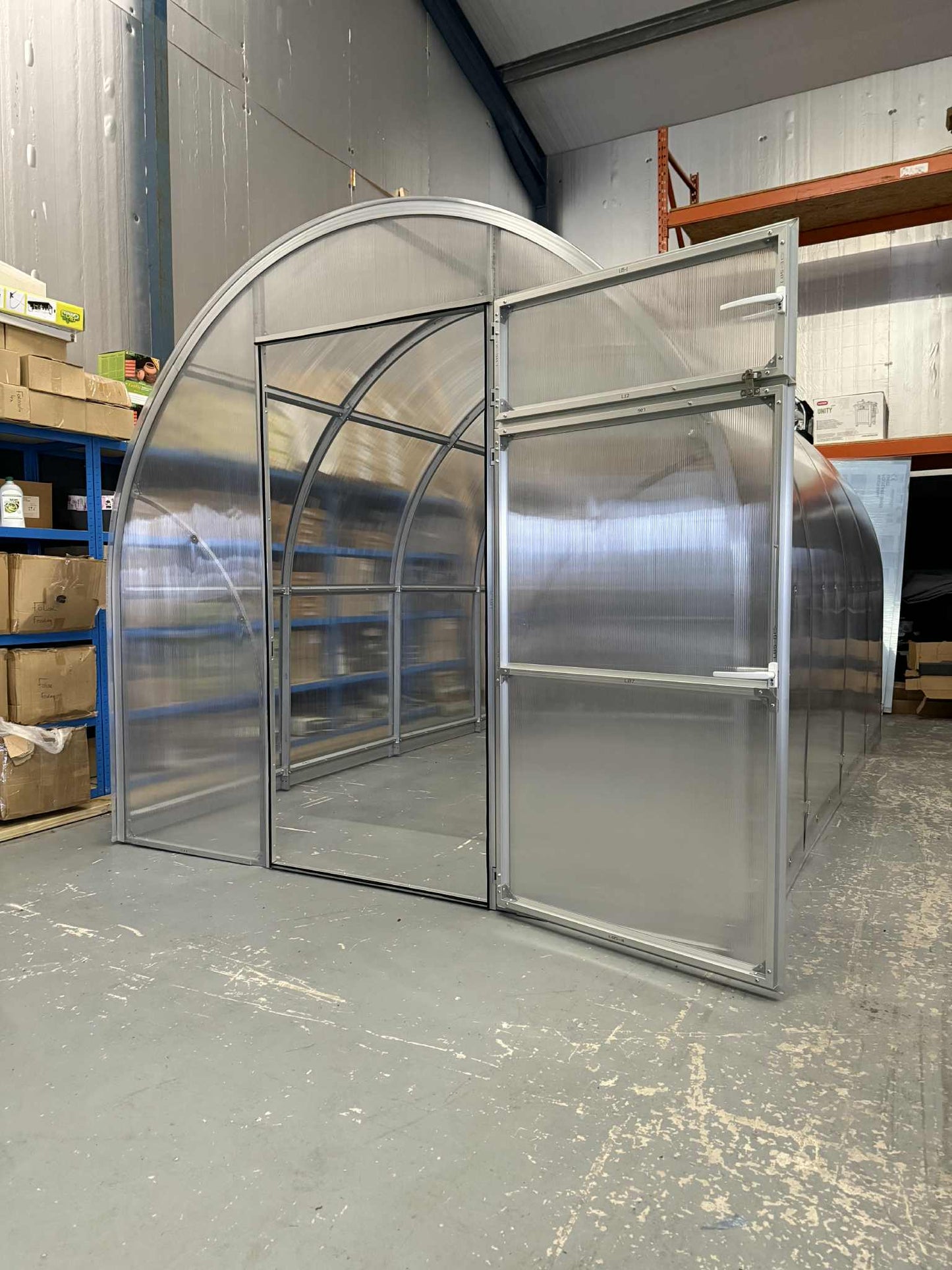 Metallic Sigma 250 (Gen III) greenhouse structure in a warehouse setting with shelves and boxes in the background.