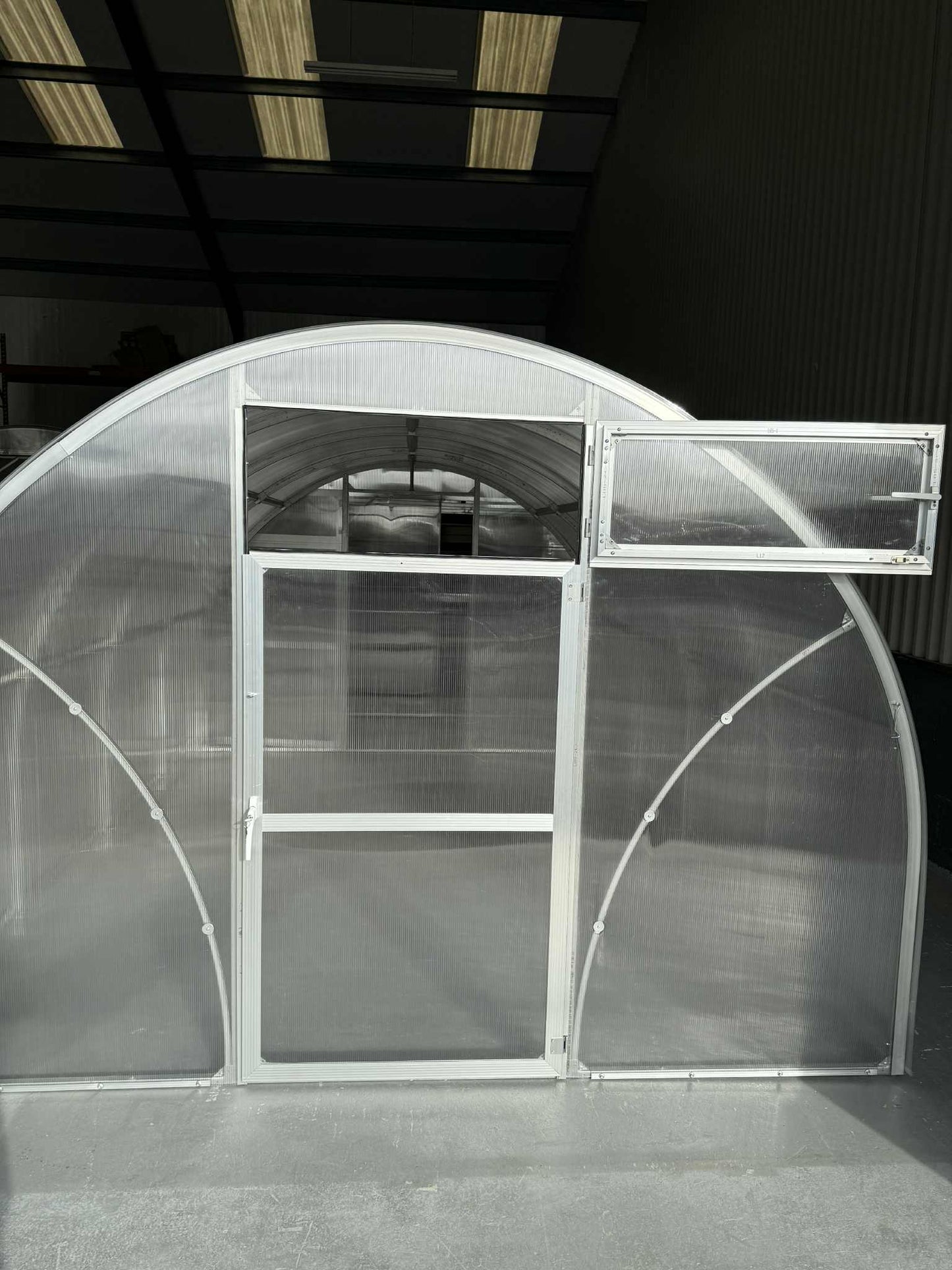  Sigma 300 (Gen III) greenhouse with a curved roof and transparent panels in a dark warehouse setting.