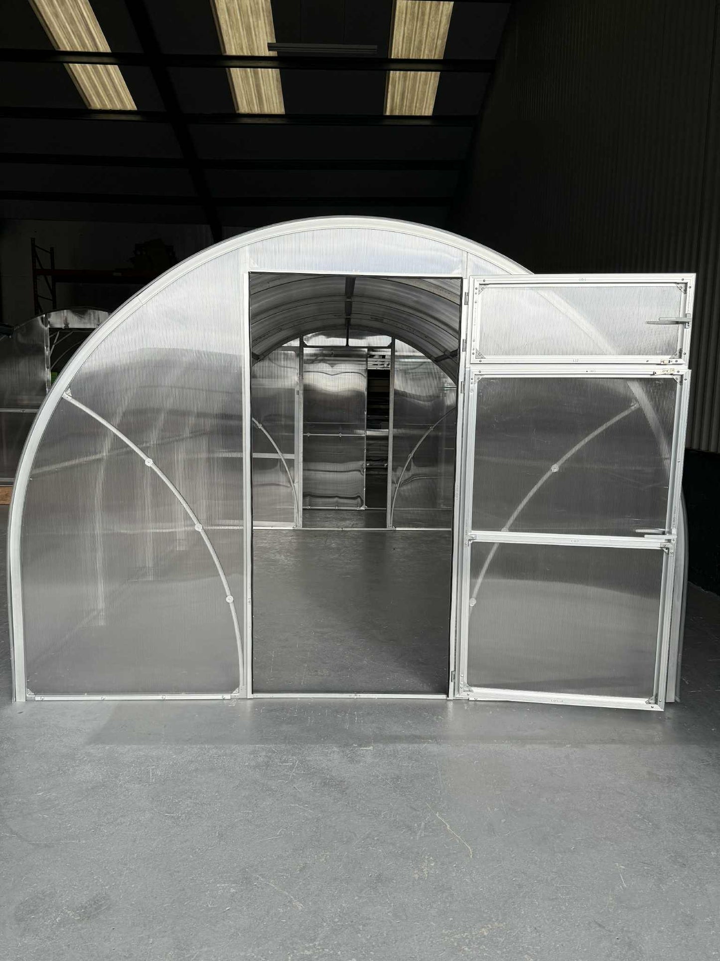 Transparent  Sigma 300 (Gen III) greenhouse structure with open doors in a dark indoor setting