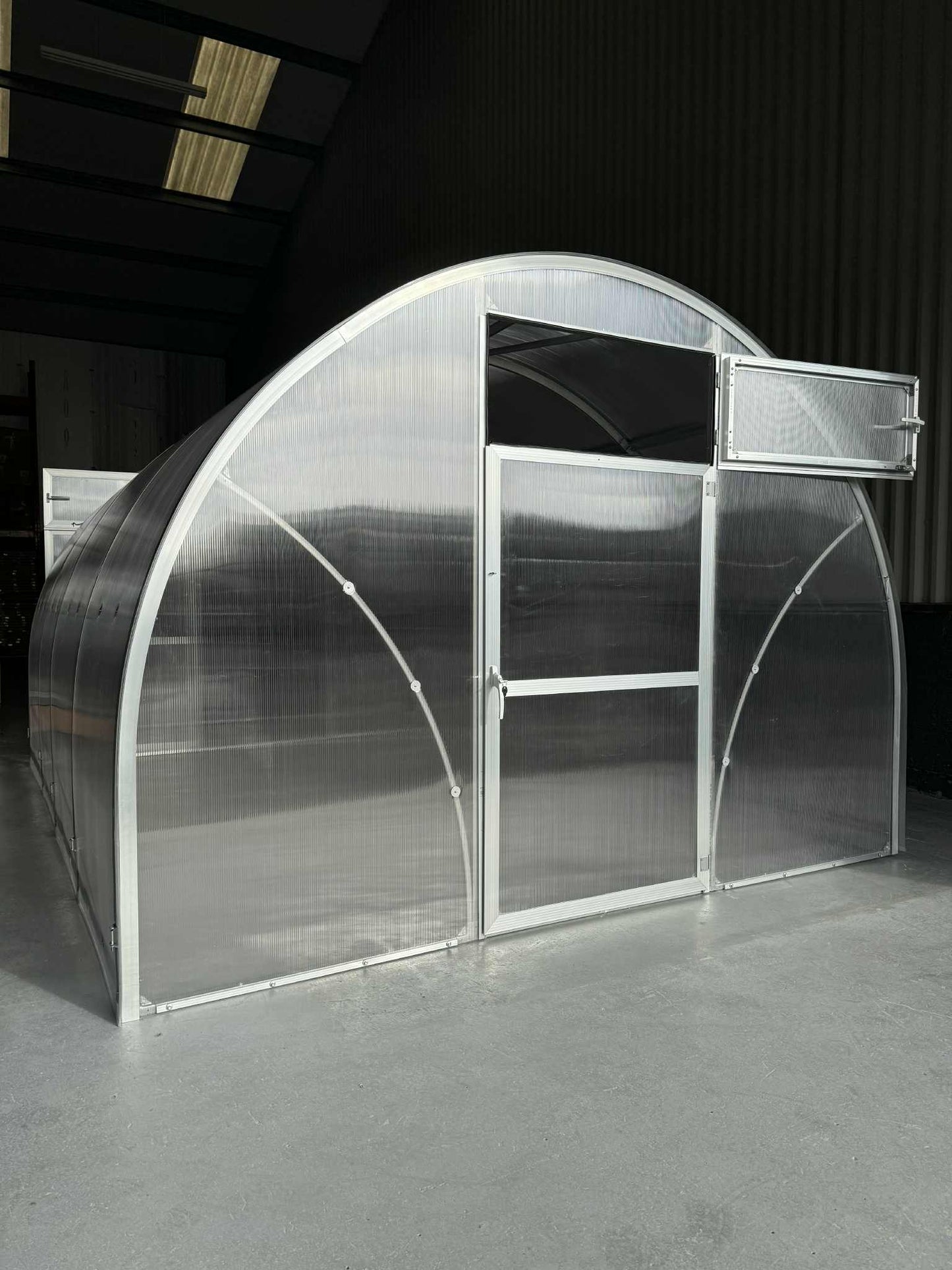 Clear polycarbonate Sigma 300 (Gen III) greenhouse with metal frame on a dark background